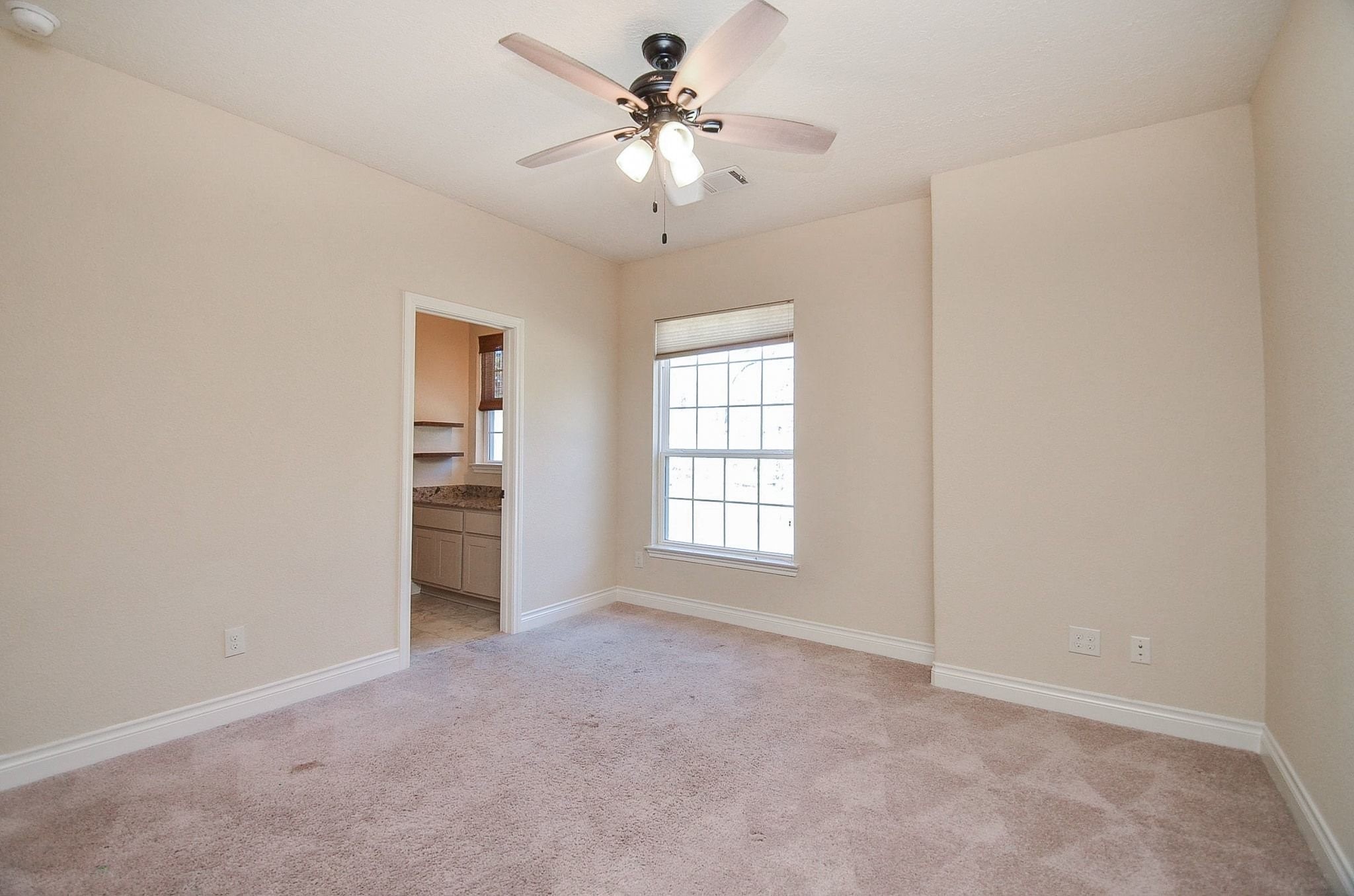 13327 Little Ranch Road Cypress, TX 77429 - Photo 27 of 49 This bedroom features a comfortable layout with neutral finishes, plush carpeting, and a ceiling fan for added comfort. It includes convenient access to a Jack-and-Jill bathroom, making it ideal for shared use while maintaining privacy.