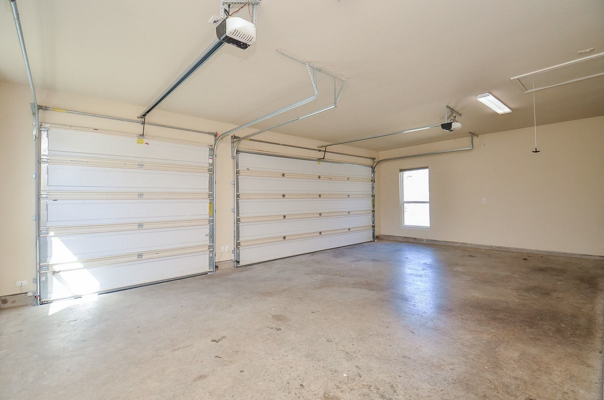 13327 Little Ranch Road Cypress, TX 77429 - Photo 36 of 49 A spacious, clean three-car garage with two large doors, overhead lighting, and a side window for natural light.