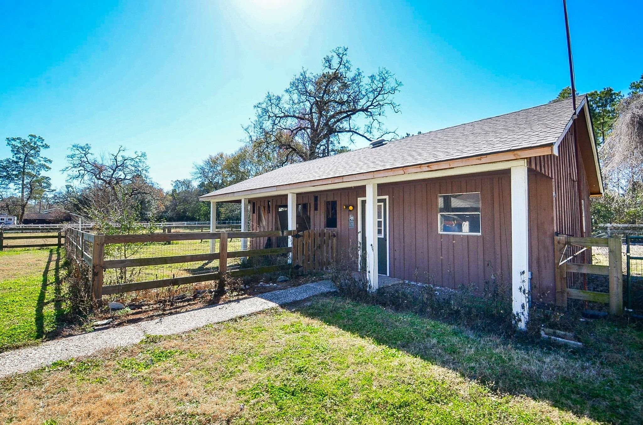 13327 Little Ranch Road Cypress, TX 77429 - Photo 41 of 49 Charming rustic barn-style outbuilding with a fenced area, surrounded by greenery, offering a peaceful rural setting. Ideal for those seeking a country lifestyle.