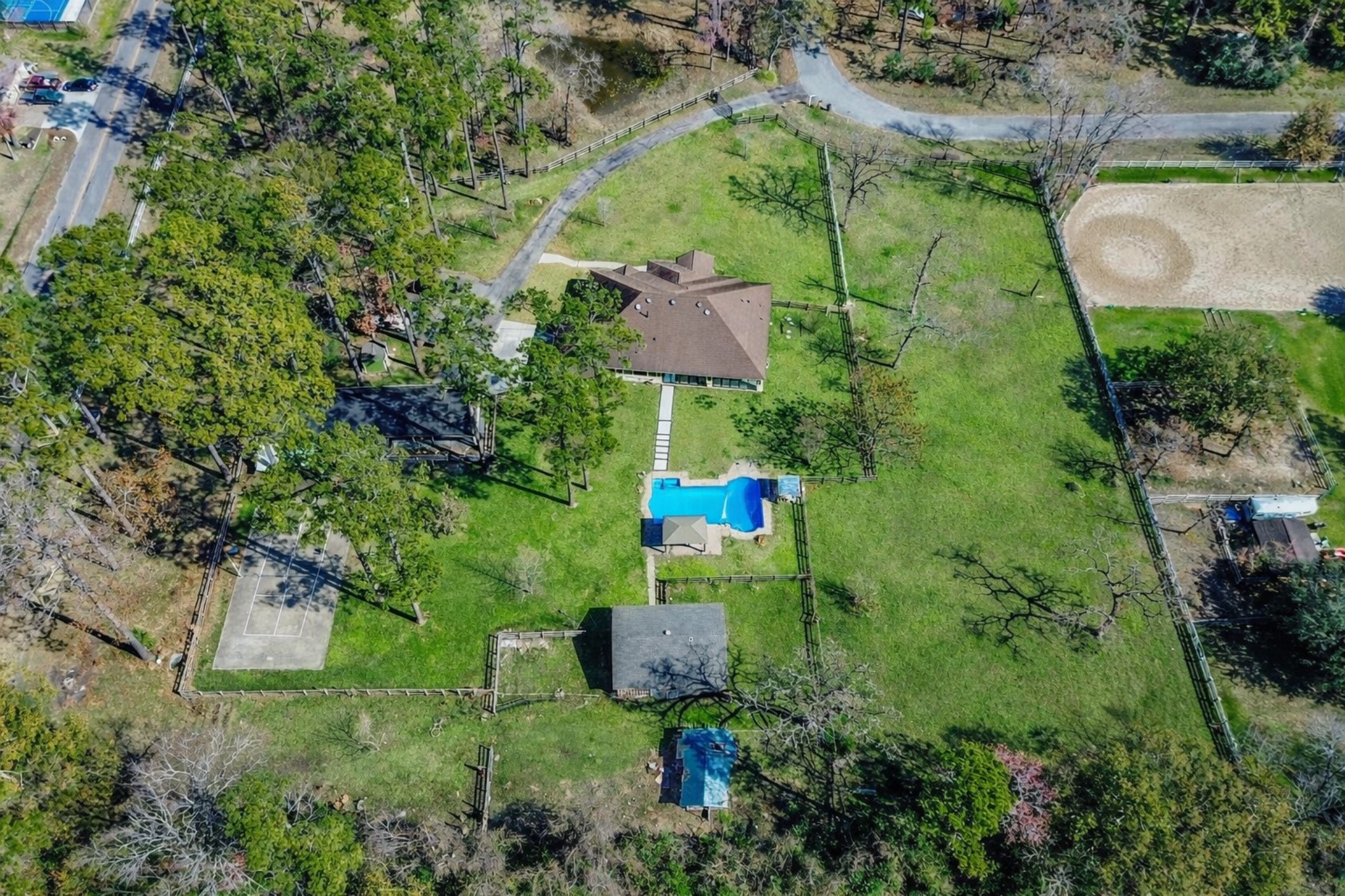 13327 Little Ranch Road Cypress, TX 77429 - Photo 48 of 49 An expansive aerial view highlights this charming single-story home set on a generous, tree-lined lot that offers exceptional privacy. A long private driveway leads to the residence, which includes a barn, a pickleball court, and an additional living space. It is ideal for multi-generational living, guest accommodations, or flexible use.
