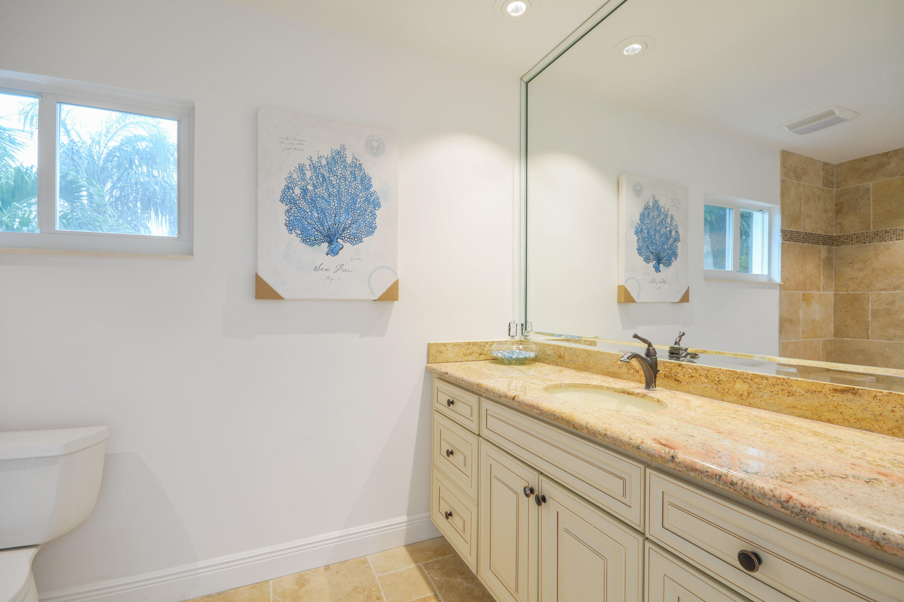 1041 Southwest 21st Avenue Boca Raton, FL 33486 - Photo 39 of 67 a bathroom with a granite countertop sink a toilet and mirror