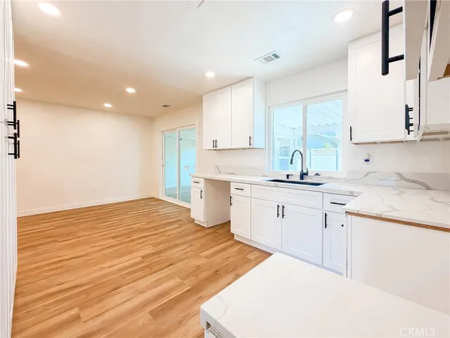 a kitchen with granite countertop a sink white cabinets and white stainless steel appliances