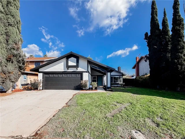 a front view of a house with a big yard and large trees