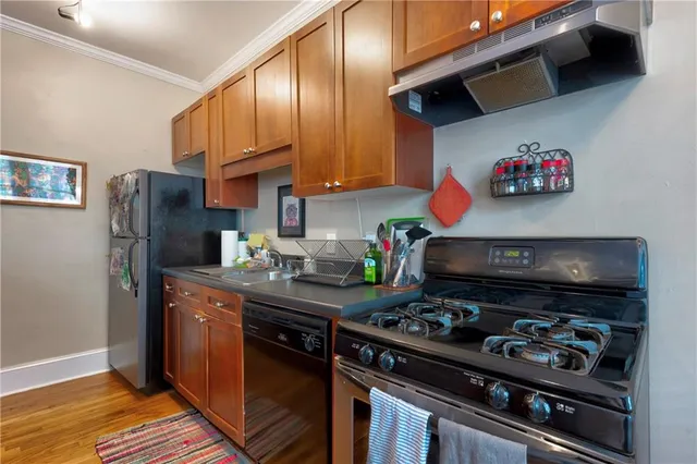 a kitchen with stainless steel appliances granite countertop a stove a sink dishwasher and cabinets with wooden floor