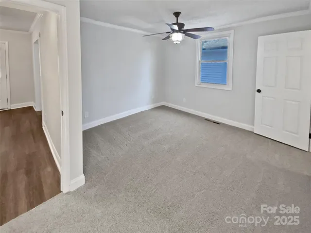 an empty room with windows and fan