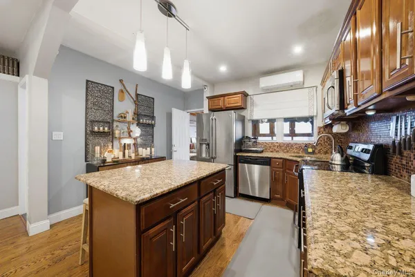 a kitchen with stainless steel appliances granite countertop a refrigerator a sink dishwasher a stove and a dining table with wooden floor