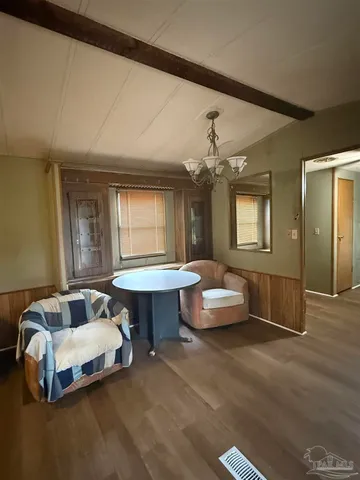 a spacious bedroom with a bed a chandelier and dresser