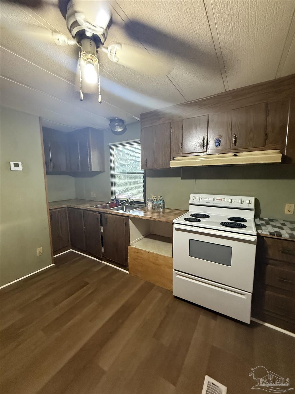 2866 Pine Forest Road, Unit 5 Cantonment, FL 32533 - Photo 5 of 10 a kitchen with a stove cabinets and wooden floor