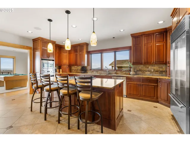 a kitchen with stainless steel appliances kitchen island granite countertop a stove a sink and a refrigerator