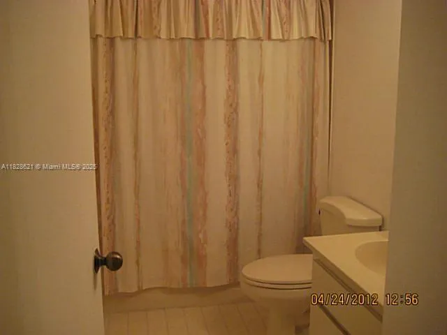 a bathroom with a toilet a sink and curtain