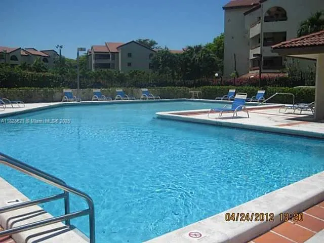 a view of swimming pool with lawn chairs and iron fence