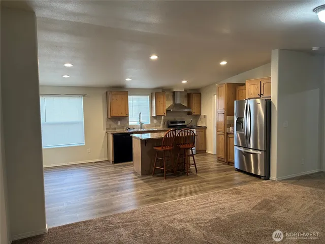 a kitchen with stainless steel appliances kitchen island granite countertop a refrigerator and a sink