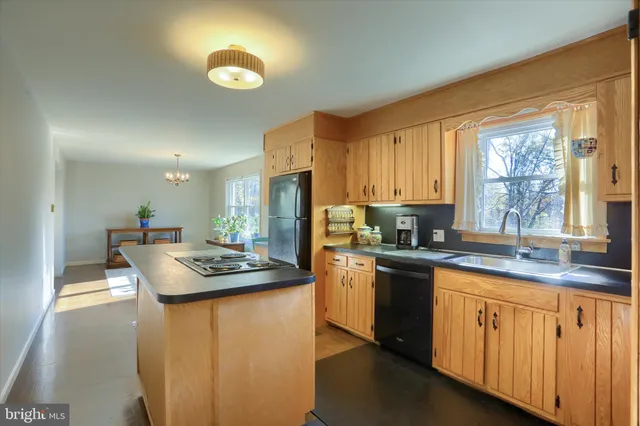 a kitchen with kitchen island granite countertop a sink appliances cabinets and a large window