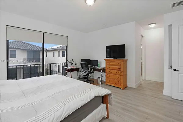 a bedroom with a bed a dresser and wooden floor