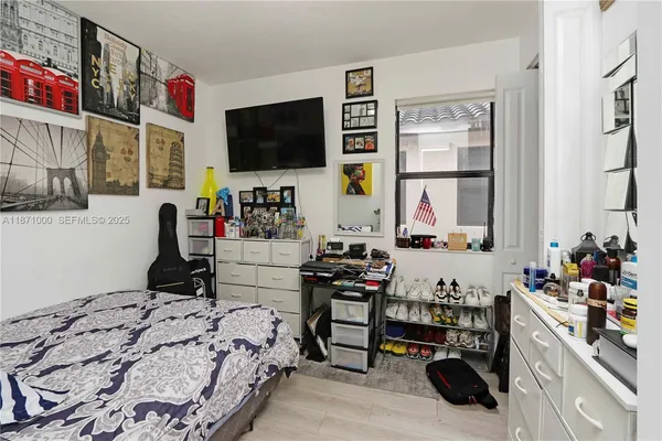 a bedroom with a bed a flat screen tv and a window