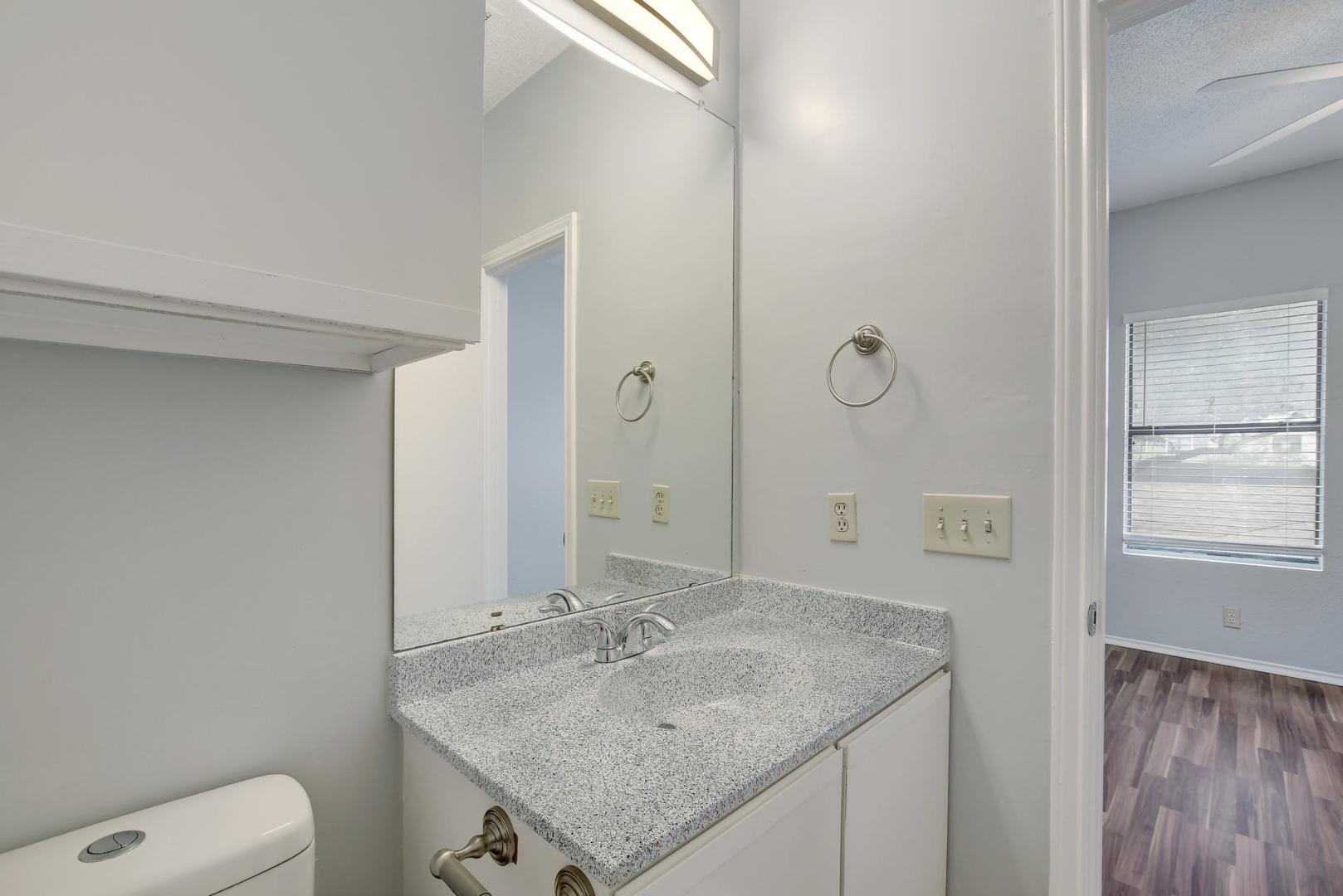 2804 Rio Grande Street, Unit 310 Austin, TX 78705 - Photo 18 of 22 A well-appointed bathroom vanity features a stone counter and ample mirror space.