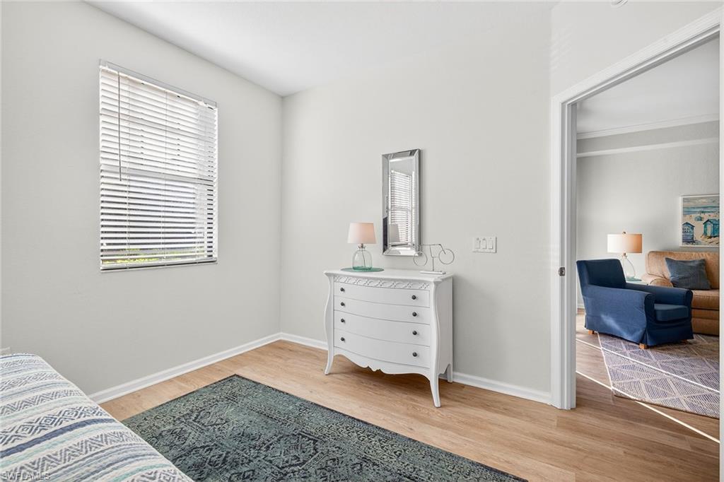 12950 Positano Circle, Unit 101 Naples, FL 34105 - Photo 19 of 34 a bedroom with a bed and wooden floor