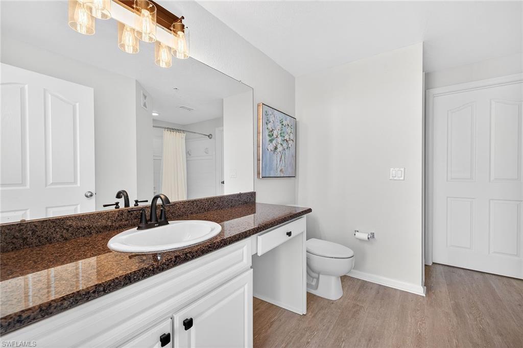 12950 Positano Circle, Unit 101 Naples, FL 34105 - Photo 21 of 34 a bathroom with a granite countertop sink a toilet a mirror and shower