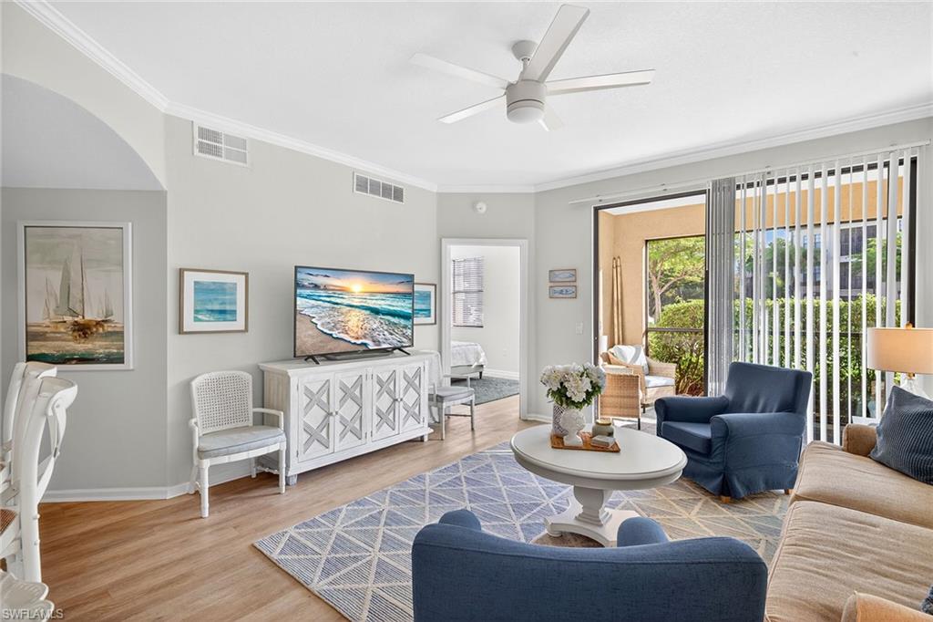 12950 Positano Circle, Unit 101 Naples, FL 34105 - Photo 5 of 34 a living room with furniture a flat screen tv and a large window