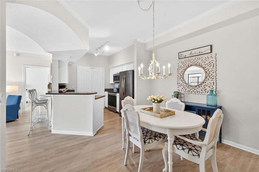 12950 Positano Circle, Unit 101 Naples, FL 34105 - Photo 6 of 34 a dining room with furniture a kitchen and chandelier