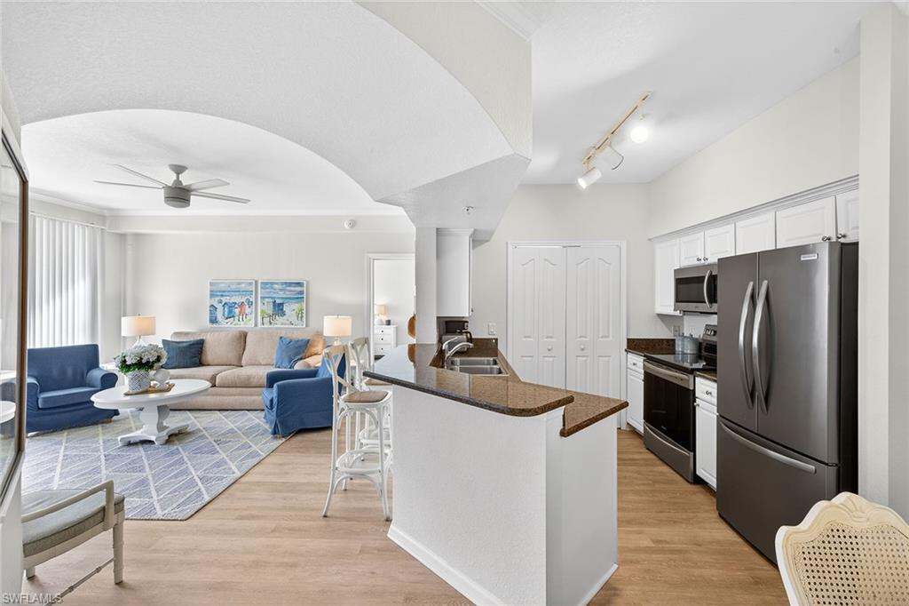 12950 Positano Circle, Unit 101 Naples, FL 34105 - Photo 9 of 34 a living room with furniture and a kitchen view