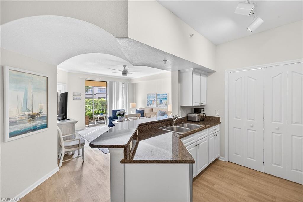12950 Positano Circle, Unit 101 Naples, FL 34105 - Photo 10 of 34 a kitchen with granite countertop a sink a counter top space and stainless steel appliances