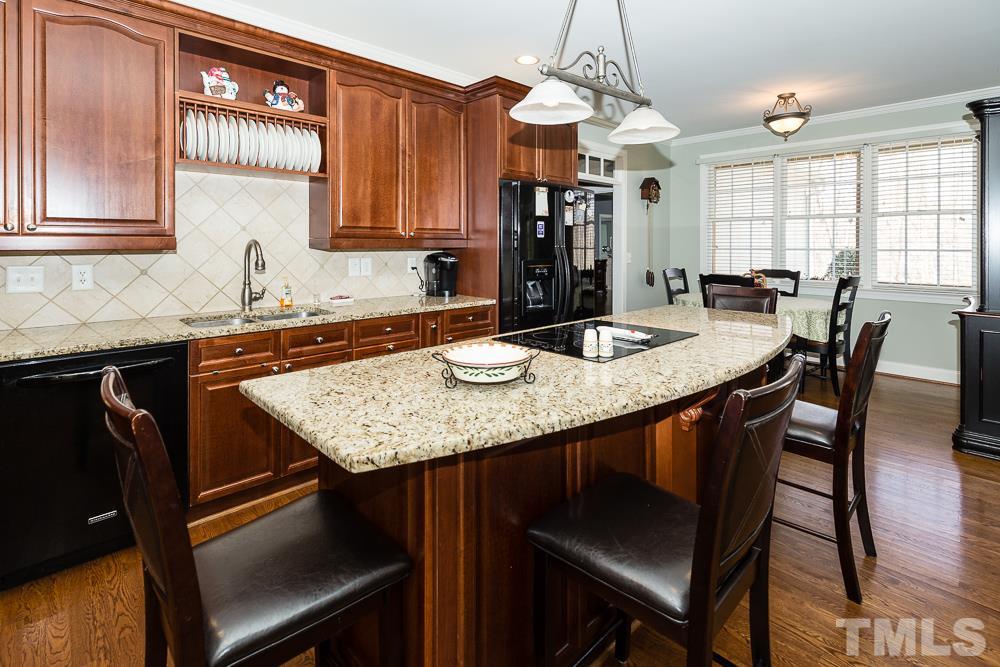 5109 Indigo Moon Way Raleigh, NC 27613 - Photo 11 of 24 a kitchen with granite countertop a table chairs stove and cabinets