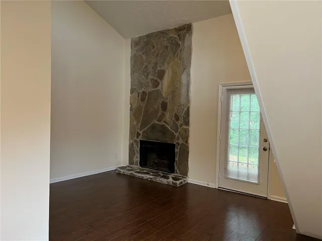 an empty room with wooden floor fireplace and windows