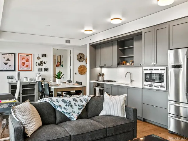 a living room with stainless steel appliances furniture and a kitchen view
