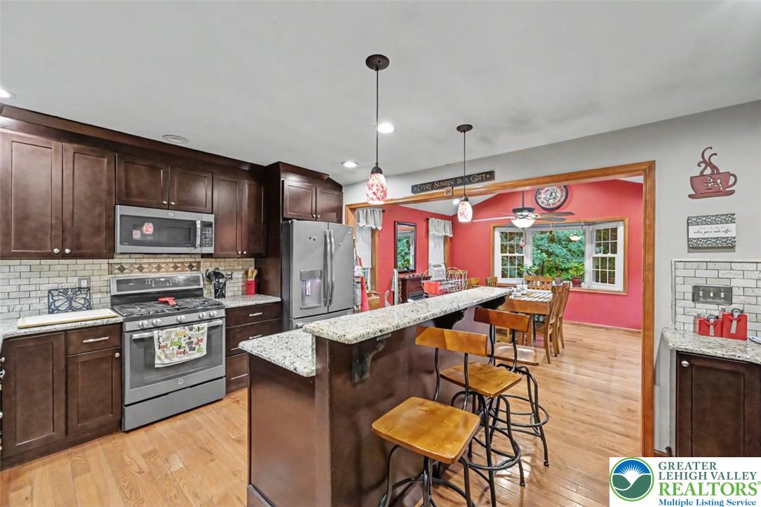 386 Upper Rdg Drive Effort, PA 18330 - Photo 7 of 56 A vibrant eat-in kitchen with rich cabinetry, granite counters, and seamless flow into a dining area.