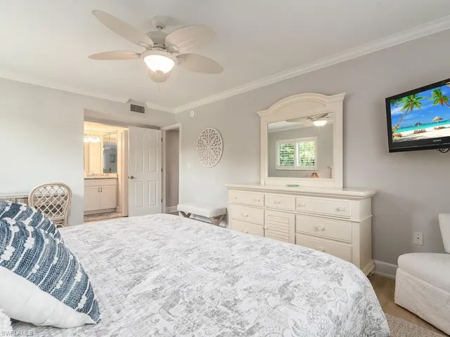 a bedroom with a bed and a tv on the dresser