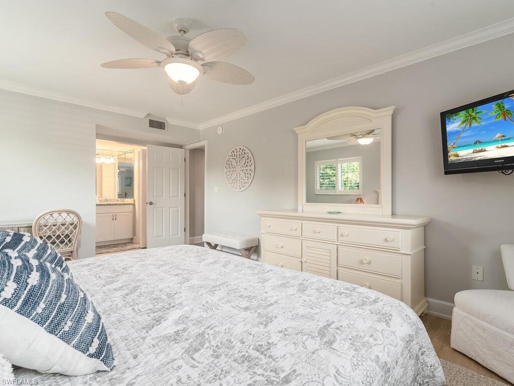 4180 Crayton Road, Unit E7 Naples, FL 34103 - Photo 13 of 35 a bedroom with a bed and a tv on the dresser