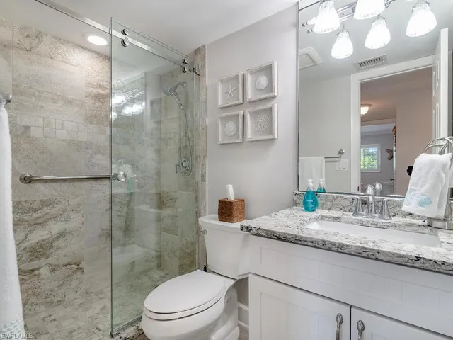 a bathroom with a granite countertop sink toilet a mirror and shower