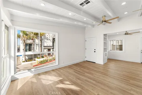 a view of a livingroom with wooden floor a ceiling fan and windows