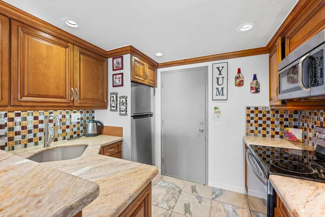 a kitchen with stainless steel appliances granite countertop a sink and a refrigerator
