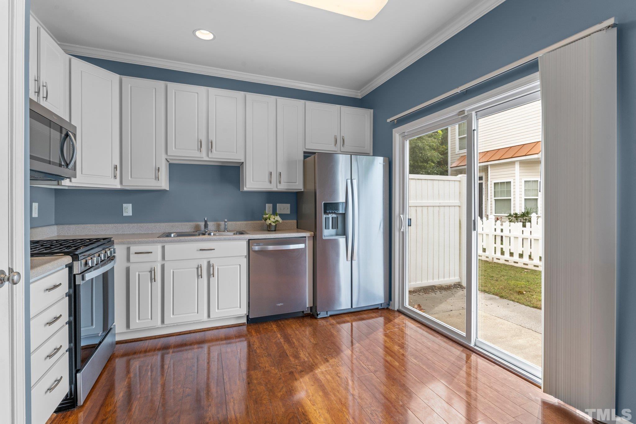 11720 Coppergate Drive, Unit 100 Raleigh, NC 27614 - Photo 5 of 22 a kitchen with a refrigerator a stove top oven and white cabinets