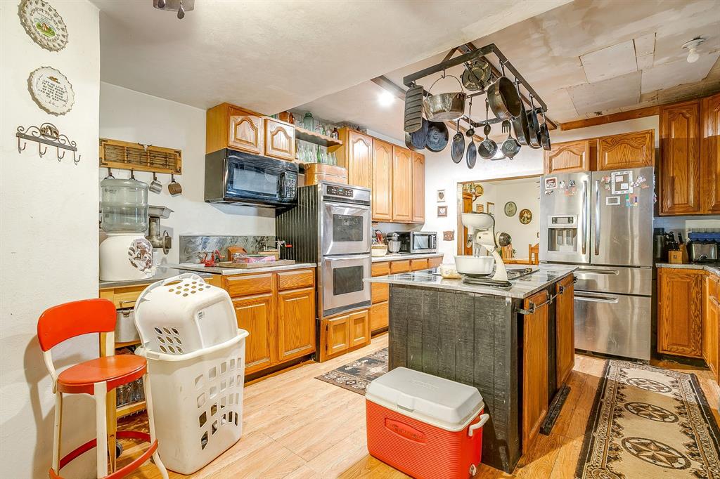 1035 Summit Drive Springtown, TX 76082 - Photo 22 of 38 Kitchen featuring light wood finished floors, stainless steel appliances, a center island, and brown cabinetry