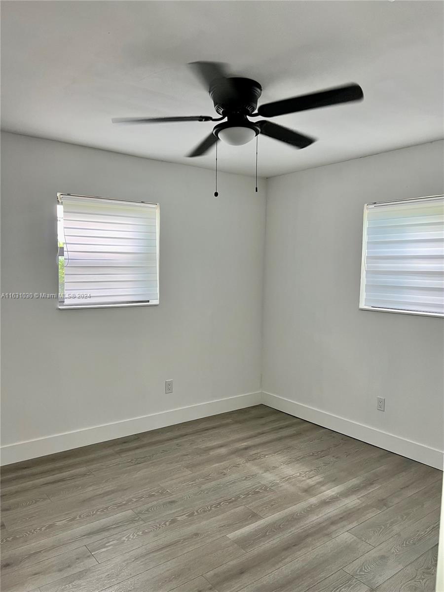 945 Curtiss Drive Opa-Locka, FL 33054 - Photo 13 of 18 an empty room with wooden floor and windows