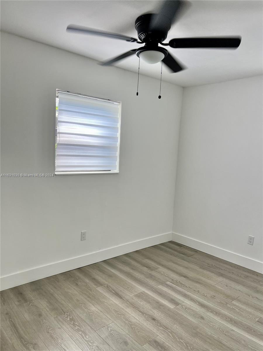 945 Curtiss Drive Opa-Locka, FL 33054 - Photo 14 of 18 a view of an empty room with wooden floor and a window