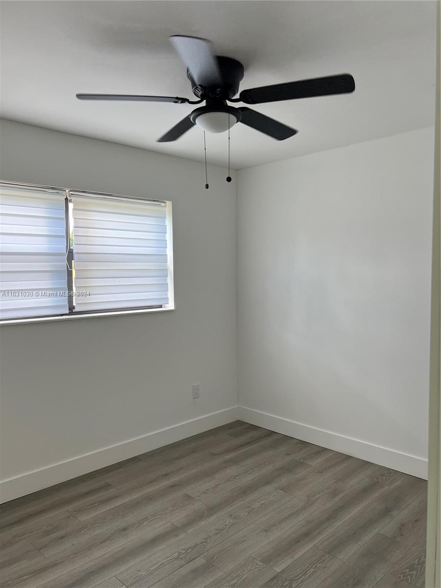 945 Curtiss Drive Opa-Locka, FL 33054 - Photo 16 of 18 an empty room with wooden floor closet and windows