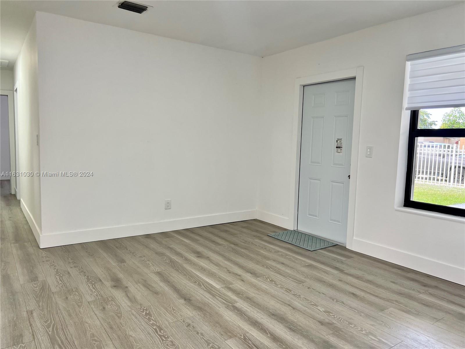 945 Curtiss Drive Opa-Locka, FL 33054 - Photo 4 of 18 an empty room with wooden floor and windows