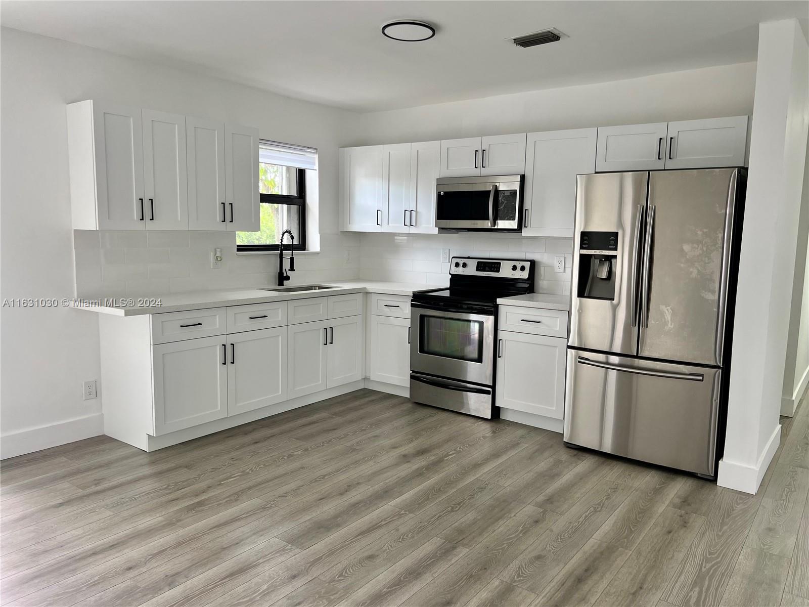 945 Curtiss Drive Opa-Locka, FL 33054 - Photo 5 of 18 a kitchen with stainless steel appliances granite countertop a refrigerator stove a sink and white cabinets