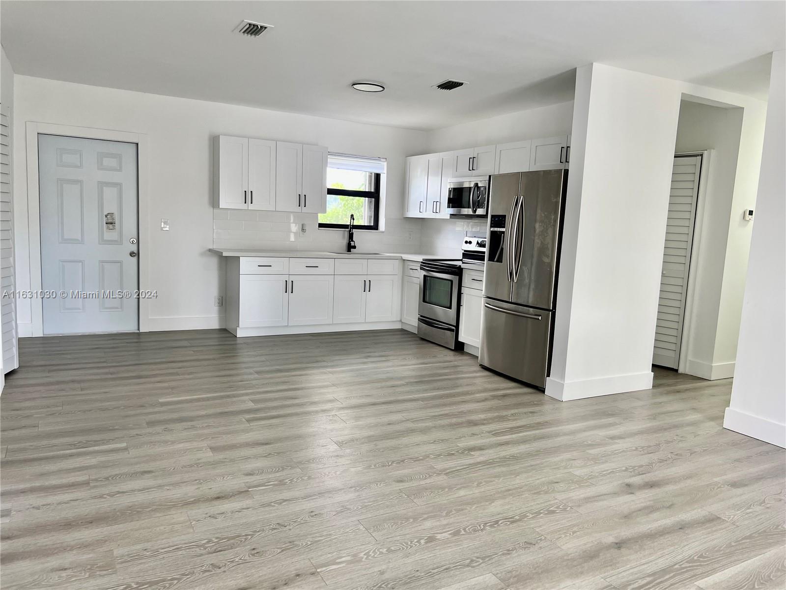 945 Curtiss Drive Opa-Locka, FL 33054 - Photo 6 of 18 a kitchen with granite countertop a refrigerator and a stove top oven