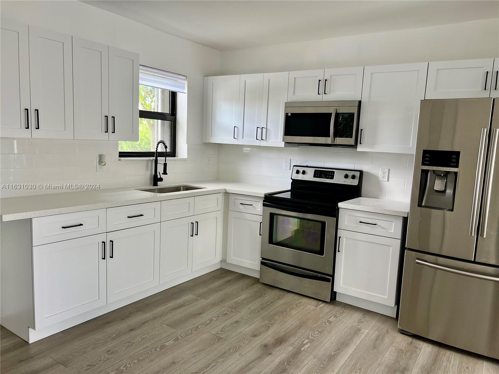 945 Curtiss Drive Opa-Locka, FL 33054 - Photo 7 of 18 a kitchen with white cabinets stainless steel appliances and sink
