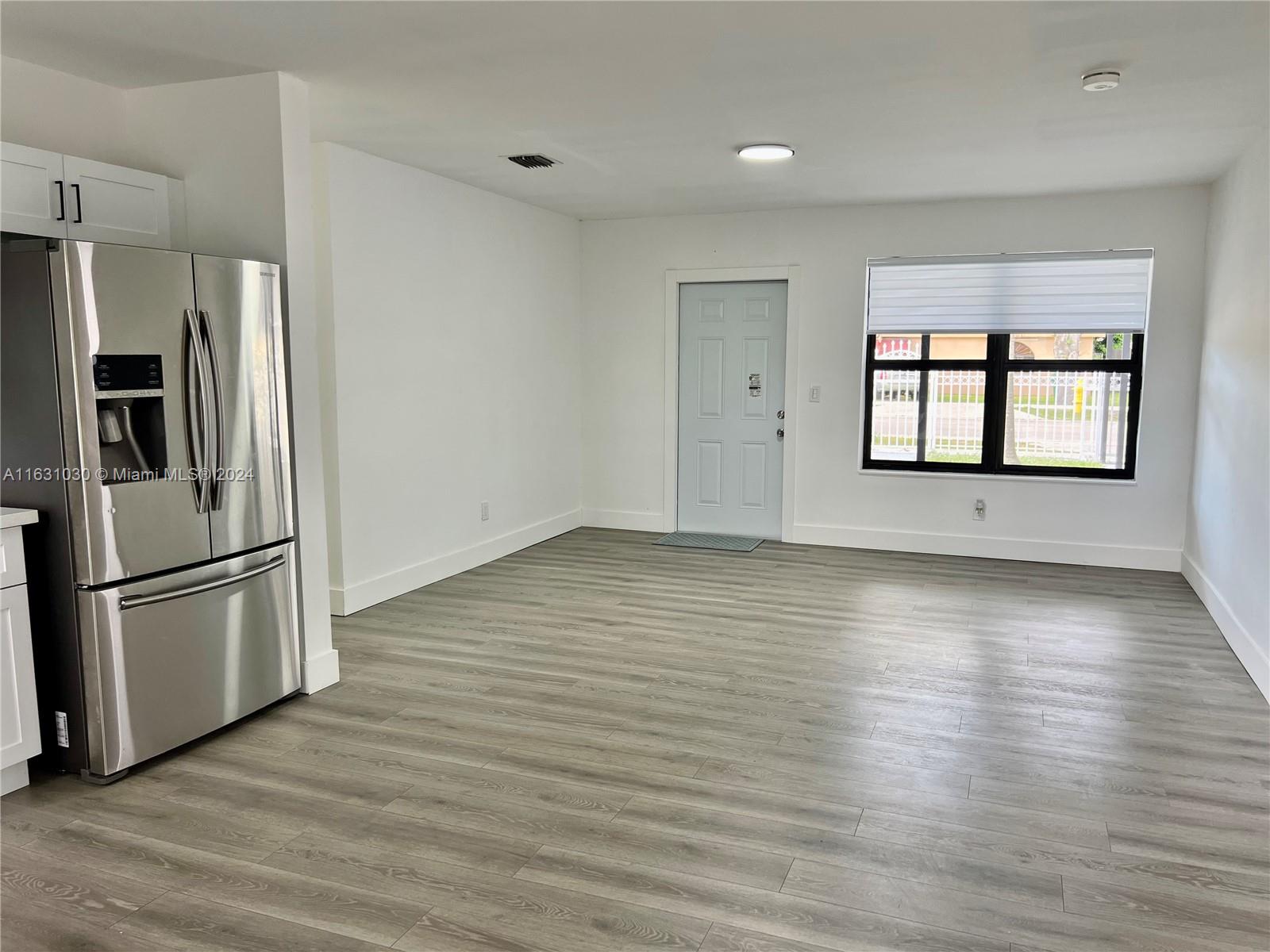 945 Curtiss Drive Opa-Locka, FL 33054 - Photo 8 of 18 a view of a kitchen with stainless steel appliances wooden floor and a large window