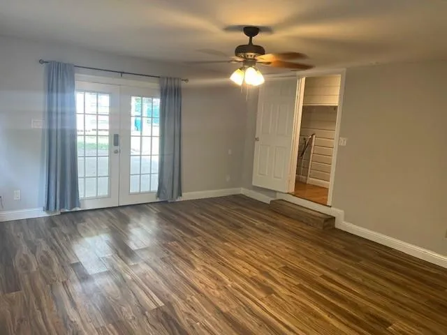 a view of an empty room with wooden floor and a window