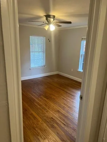 a view of empty room with wooden floor and fan