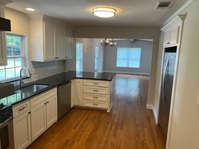 a kitchen with granite countertop white cabinets and wooden floor