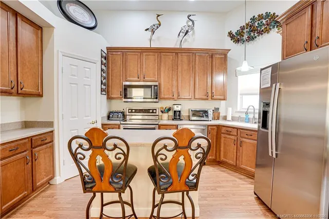 a kitchen with stainless steel appliances granite countertop a dining table chairs refrigerator and sink