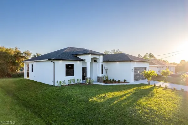 a front view of house with yard and trees in the background